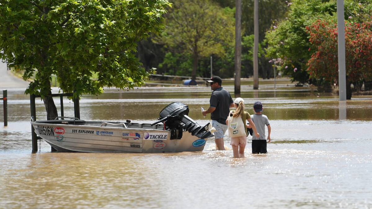 A family in Gunnedah walk through flood water to access their boat in the town's low lying areas. Picture by Gareth Gardner