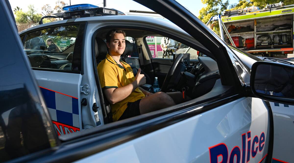 Farrer Memorial Agricultural High School student Zak Power tries on a police patrol car for size, during the launch of the You Should Be a Cop in Your Hometown and Youth Program in Tamworth. Picture by Gareth Gardner