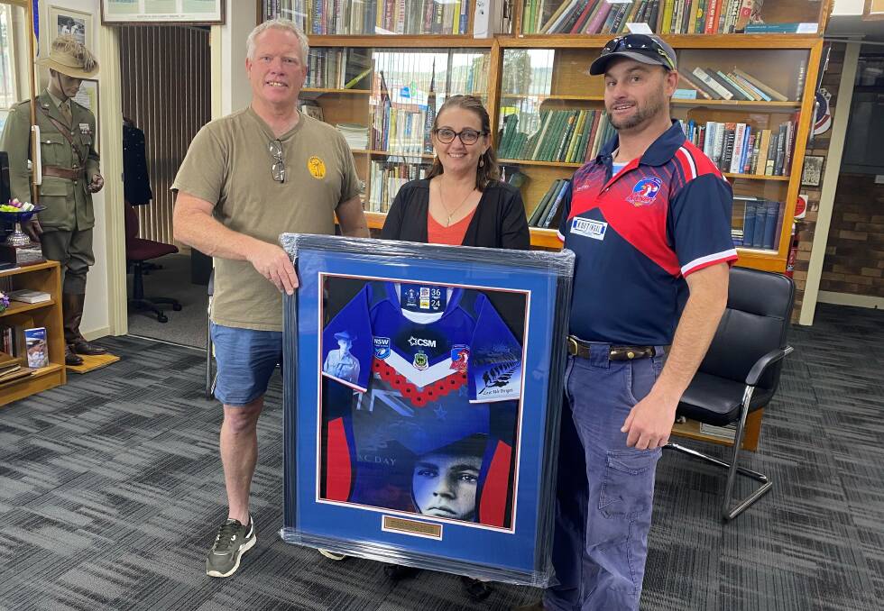ProTen's Julian Johnson (left) and Kootingal-Moonbi president Lad Jones (right) present the Tamworth RSL Sub-Branch's Jayne McCarthy with a framed Roosters jumper after raising $6912.50 at their charity auction day for the Sub-Branch.