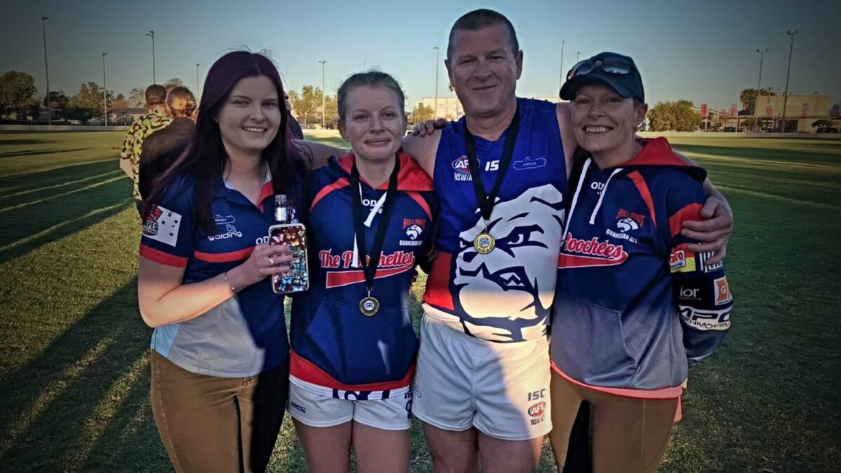 Ewington celebrates the Bulldogs' successful 2020 men's and women's premierships with his daughters, Laura and Kelly, and his wife, Nerieda. 