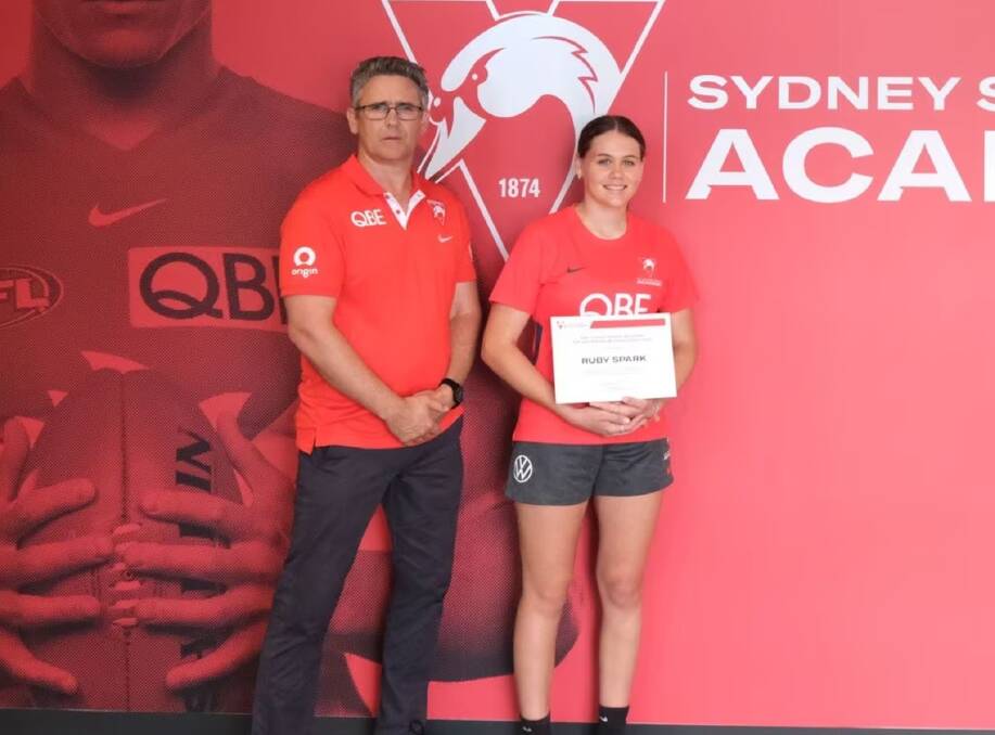 Ruby Spark is all smiles next to Leon Cameron after receiving her Swans Academy Scholarship. Picture by Sydney Swans.