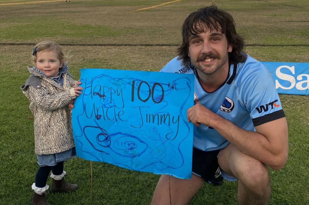 James Albert with niece Reggie and the sign she made for him for his recent 100th game. Picture Supplied.