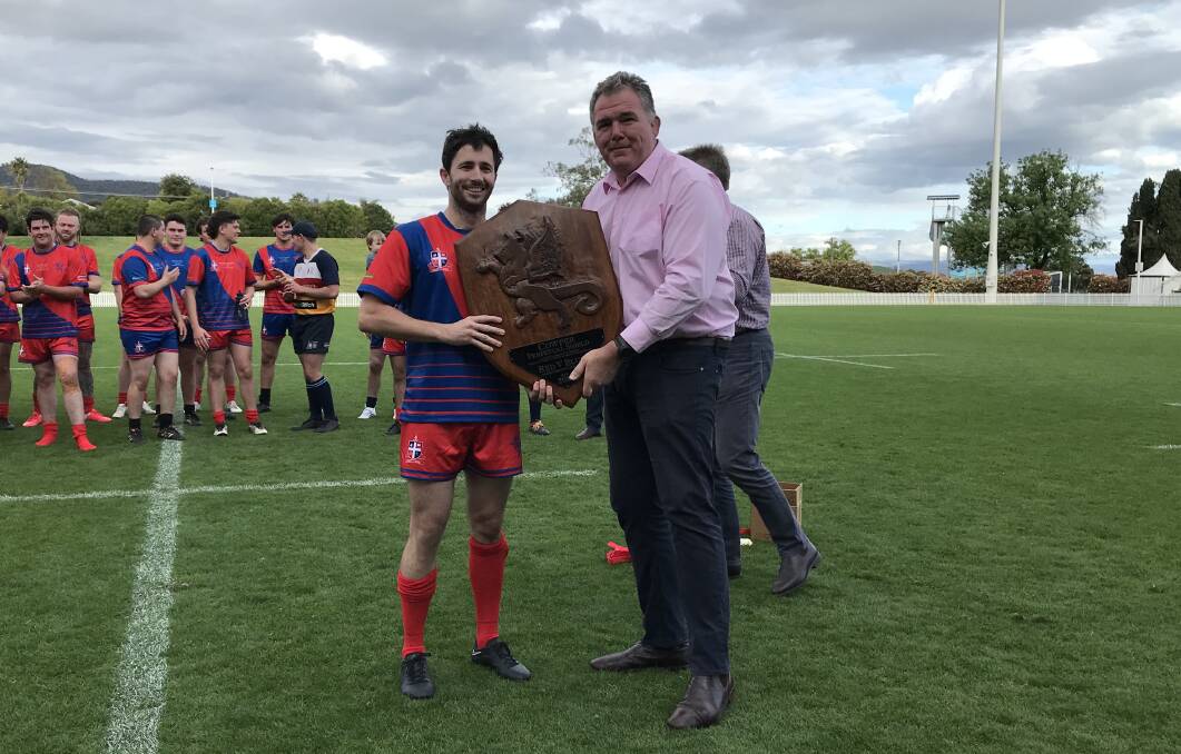 Victorious Red team captain Michael Handley receives the Cowper Perpetual Shield from former Wallaby and special guest Owen Finegan. 