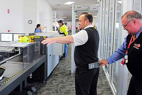 GLITCHES BEING IRONED OUT: Tamworth’s Matt Endemi, left, was one of hundreds of people scanned by MSS security employee David Wright at Tamworth Airport. Photo: Robert Chappel 030712RCB02